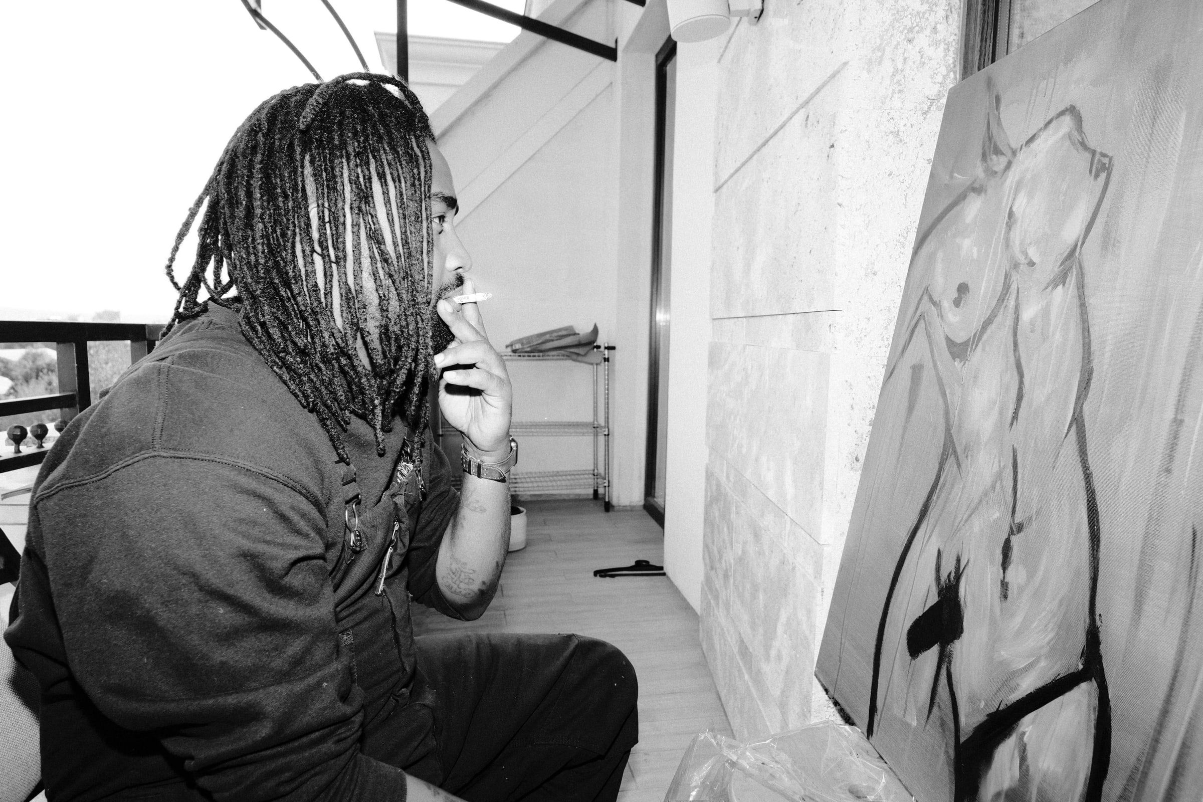 Dawit in profile, smoking and studying a painting of a nude figure, in black and white