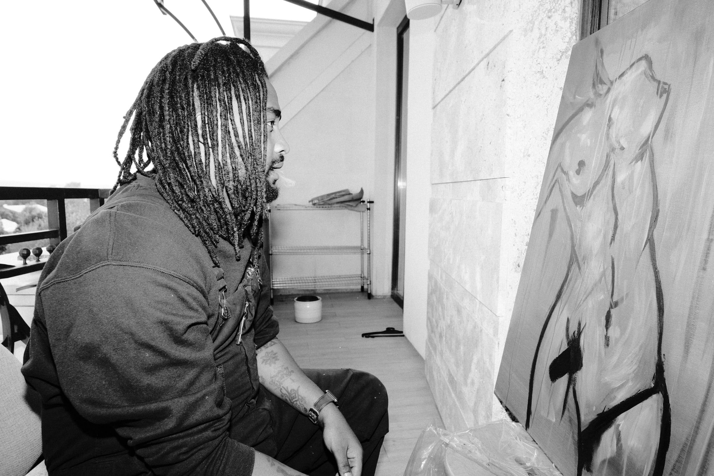 Dawit in profile, exhaling smoke in front of the same painting, in black and white